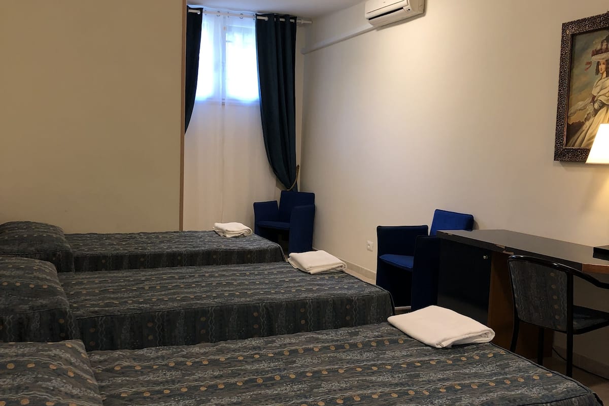 Ein Hotelzimmer mit vier Betten, einem Schreibtisch und einem Stuhl.