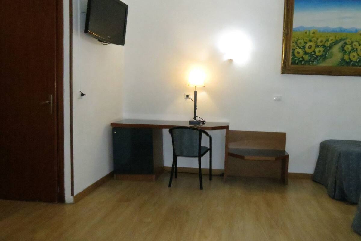 Ein Zimmer mit Schreibtisch, Stuhl und zwei Betten.