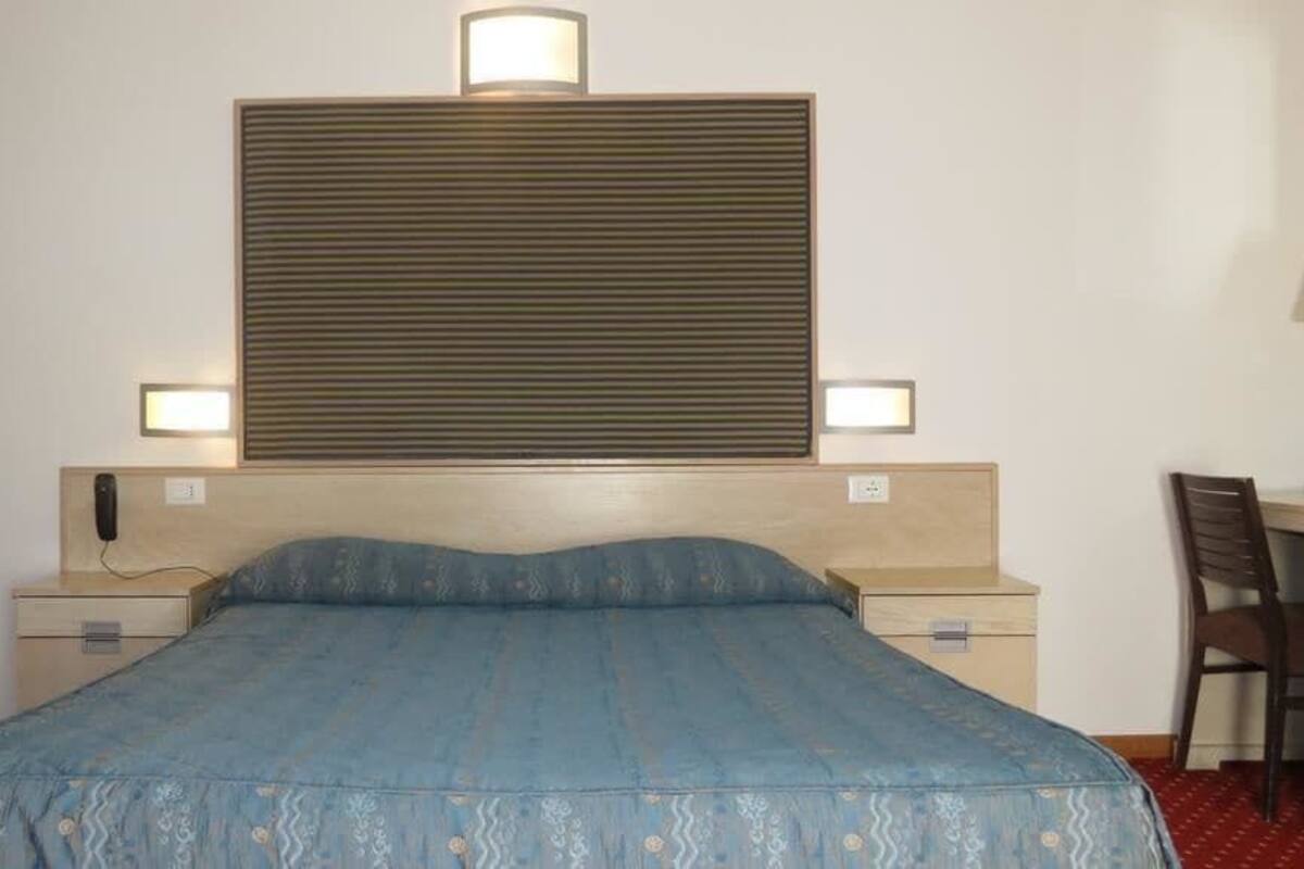 Ein Hotelzimmer mit einem Bett, Nachttischlampen, einem Schreibtisch und einem Sessel.