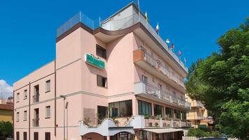 Un hotel con facciata rosa, diversi balconi e un cartello che riporta la scritta "BEL SOGNO".