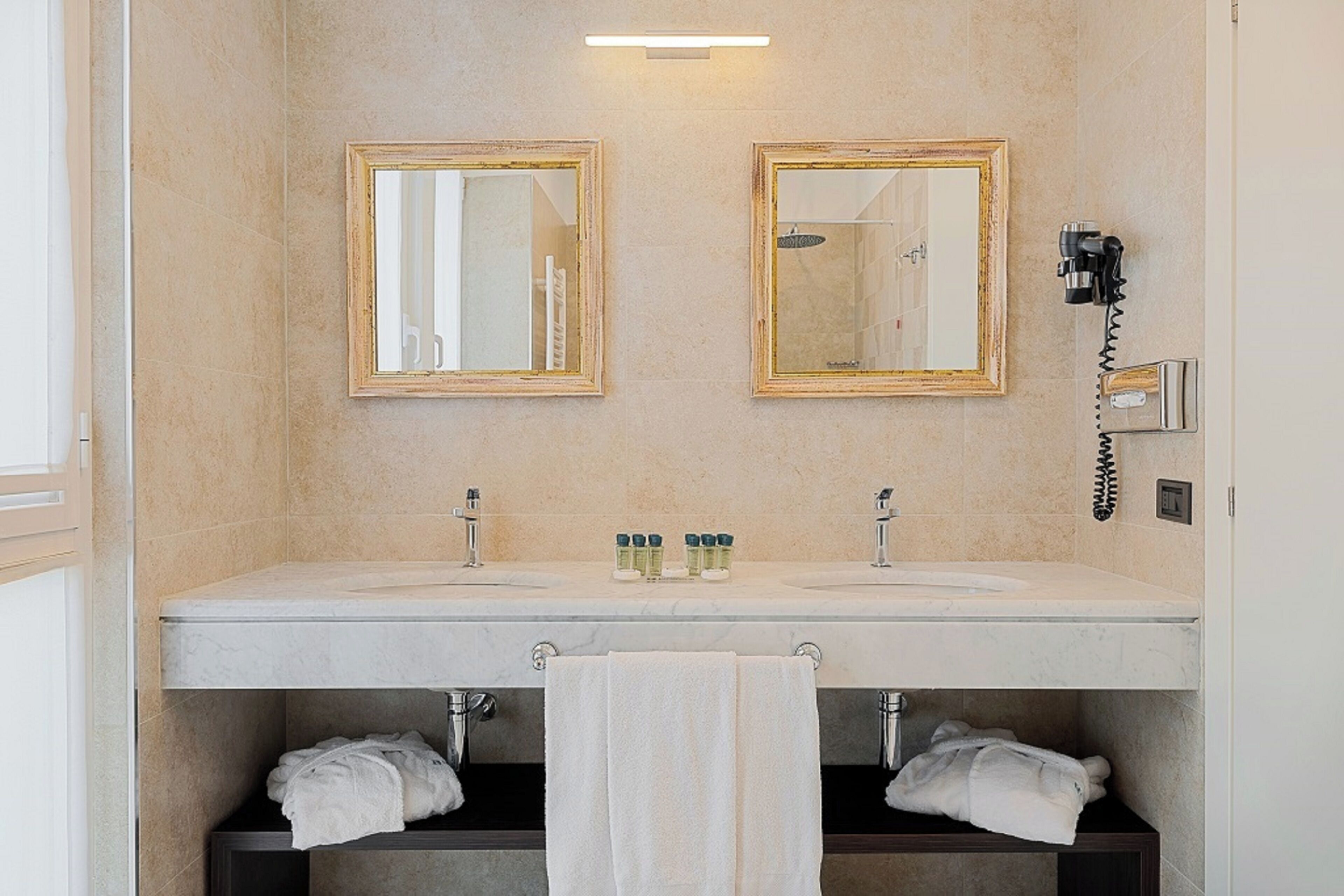 Une salle de bain avec deux lavabos, des miroirs, un sèche-cheveux et des serviettes.
