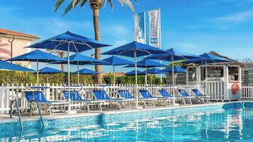 Relax by the pool surrounded by palm trees and lounge chairs.