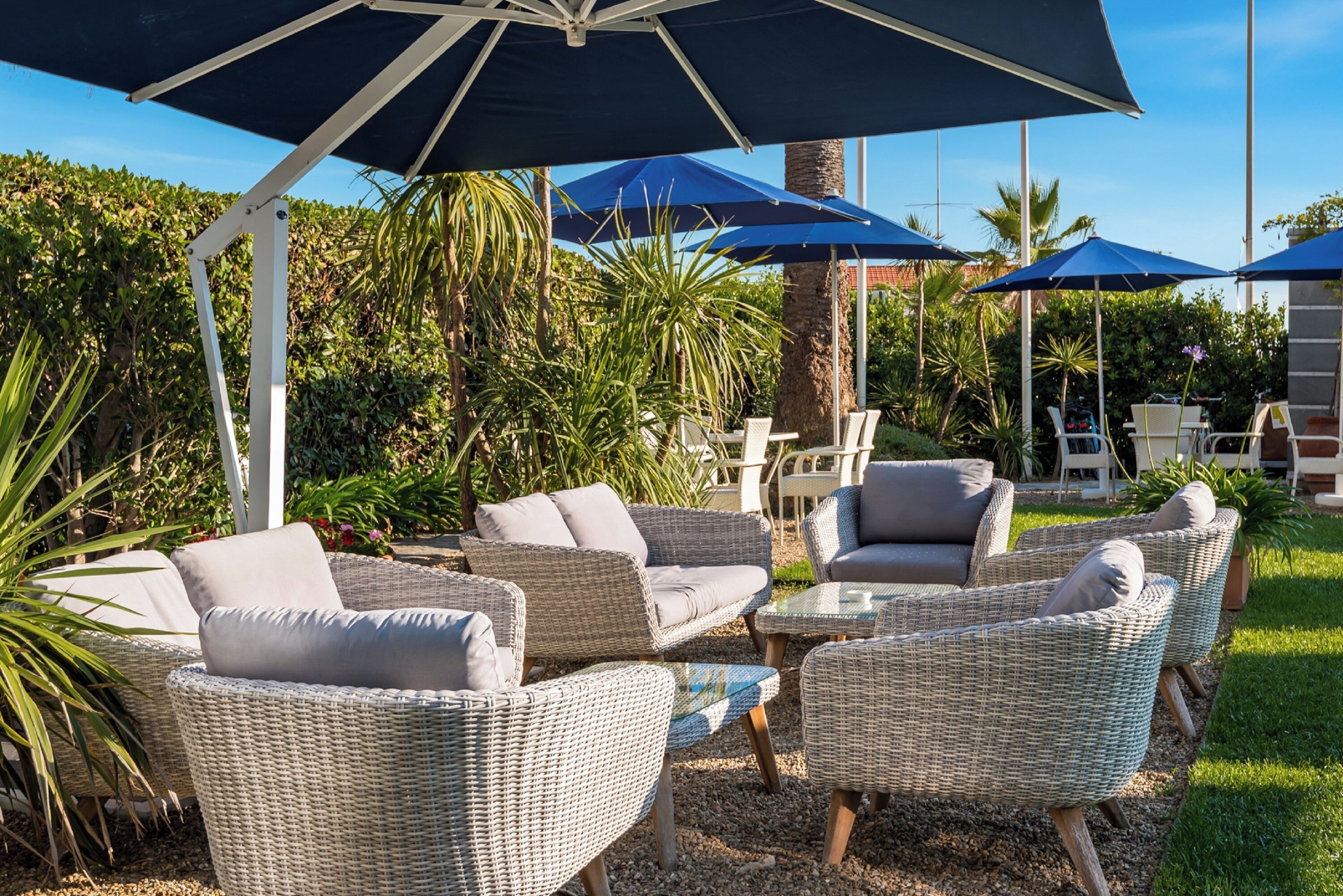 An outdoor seating area with wicker furniture and umbrellas.
