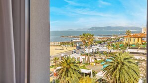 Un paisaje urbano costero con playa, palmeras y vista al mar.