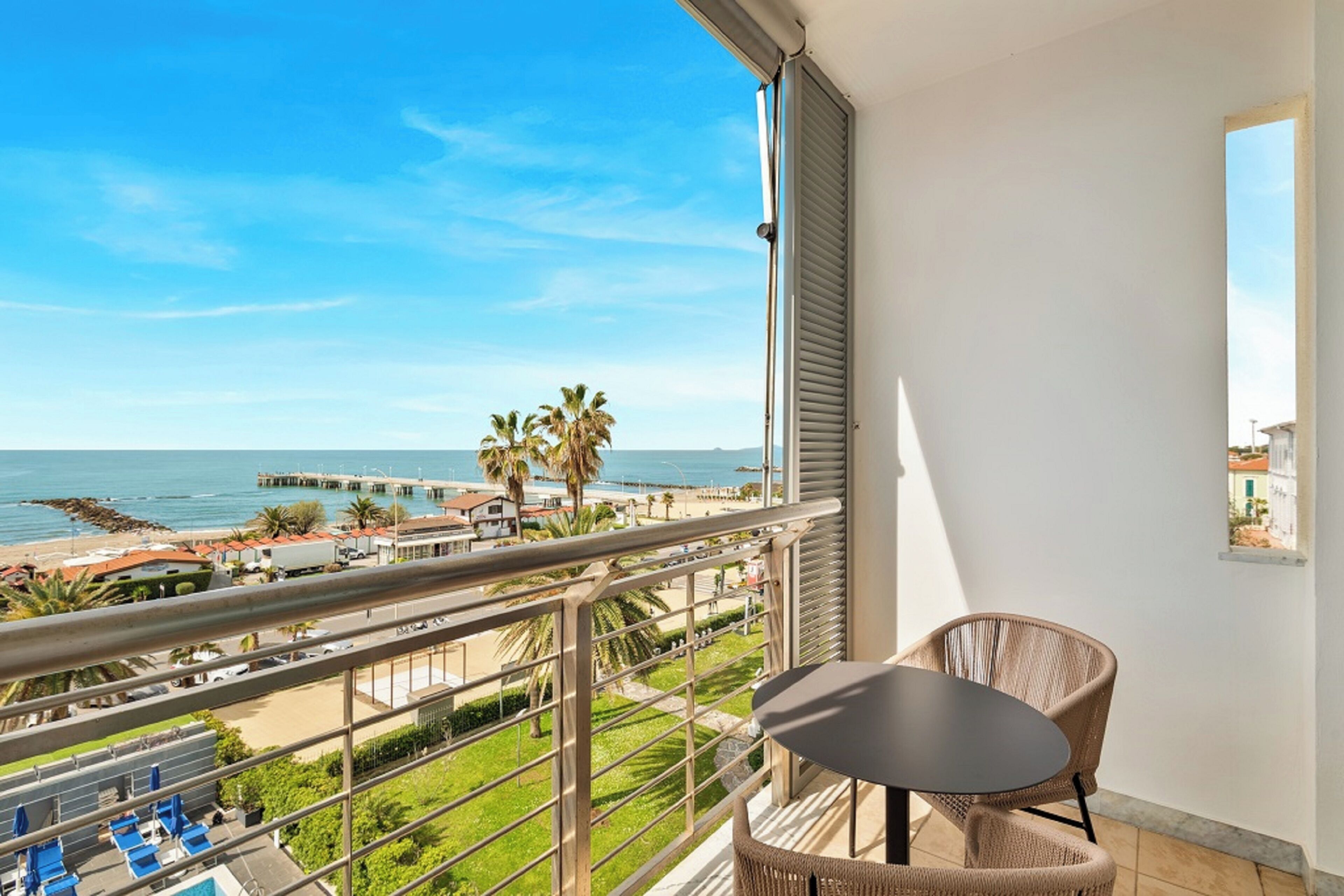 Un balcone con vista sulla spiaggia, un tavolo e delle sedie.