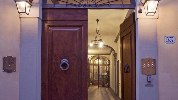 Entrada de hotel con puerta de madera, reja de hierro forjado y pasillo que conduce a una habitación.