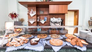 Un bufé de desayuno con diversos pasteles, una máquina de café y un aparador de madera al fondo.