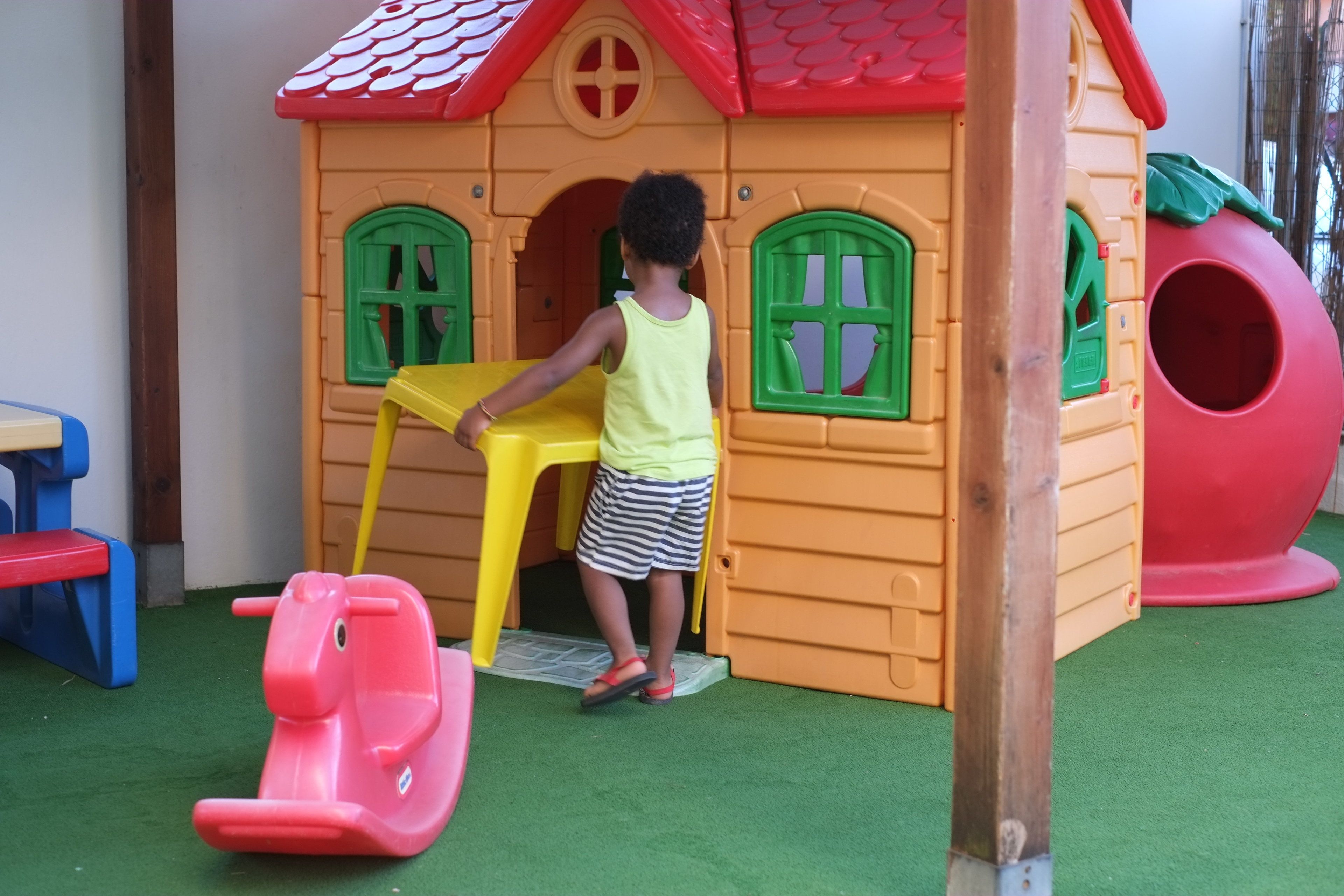 Un bambino gioca su una struttura colorata con uno scivolo e un'area giochi per arrampicarsi.