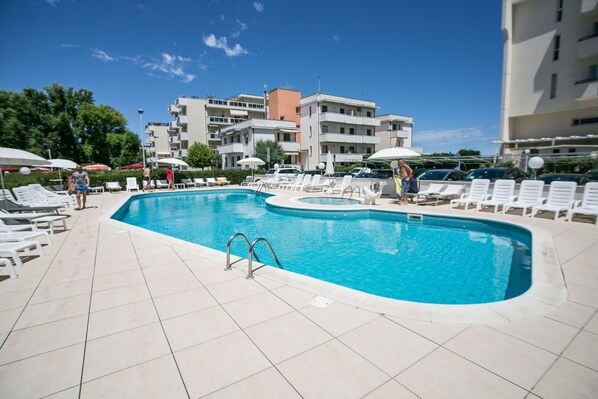 A swimming pool with sun loungers and umbrellas, surrounded by buildings. - Park Hotel Serena (Rimini)