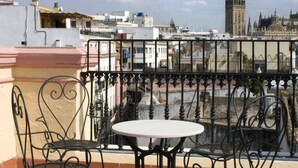 A terrace with a table and chairs, overlooking a cityscape with historic buildings and a prominent tower. - Taberna del Alabardero (Seville)