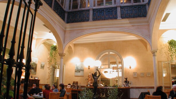 A grand lobby with high ceilings, ornate railings, and a central fountain. - Taberna del Alabardero (Seville)