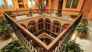 A multi-level atrium with a central courtyard, ornate railings, and potted plants. - Taberna del Alabardero (Seville)
