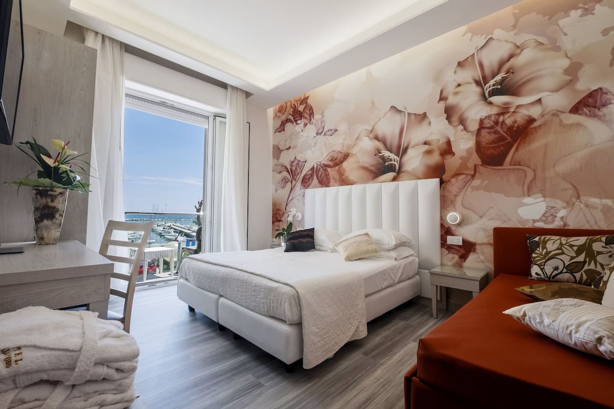 A modern hotel room with a large bed, a desk, and a view of the city.