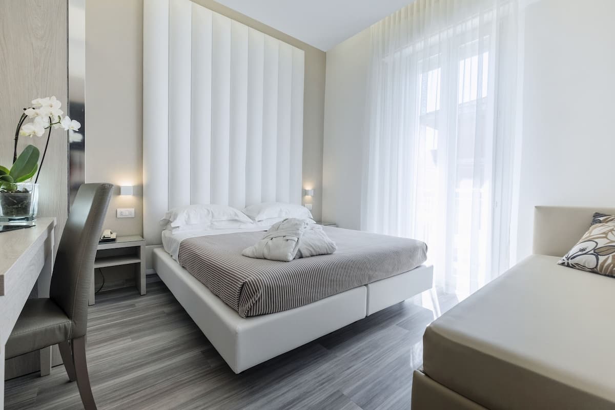 A modern hotel room with a large bed, a desk, and a chair.