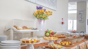A buffet setup with various food items, including cakes and pastries, and a vase of flowers. - Hotel Haway (Cattolica)