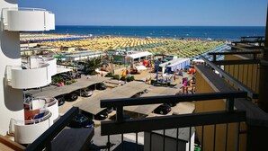 A beachside view from a balcony overlooking a crowded beach with numerous umbrellas and people. - Hotel Haway (Cattolica)