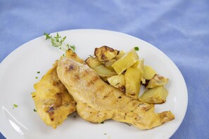 A plate with grilled chicken and roasted potatoes. - Hotel Haway (Cattolica)