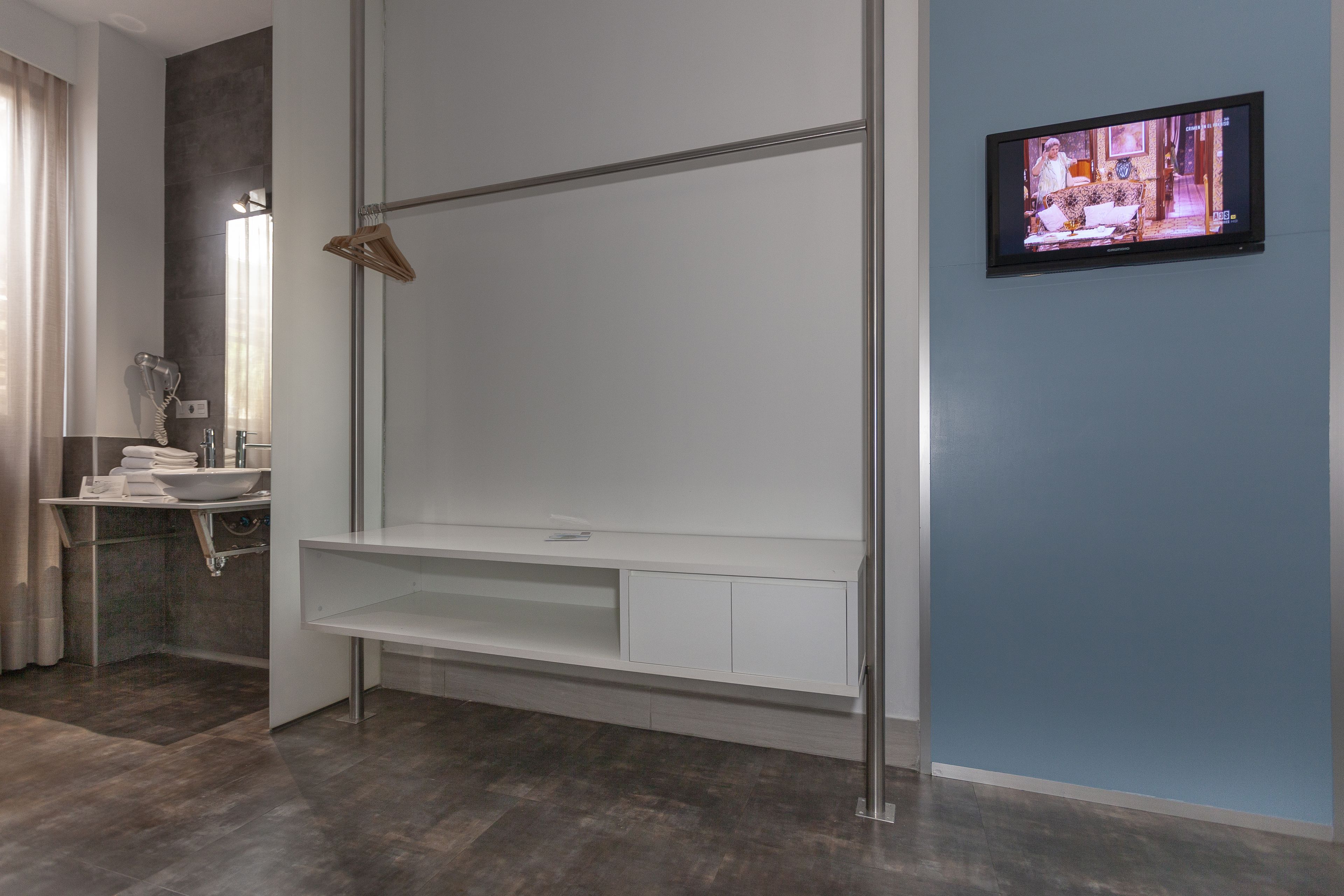 A modern bathroom with a built-in shower, a vanity with a sink, and a television mounted on the wall.