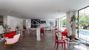 Un amplio espacio interior con varias mesas y sillas, una zona de bar y grandes ventanales con vistas al exterior.