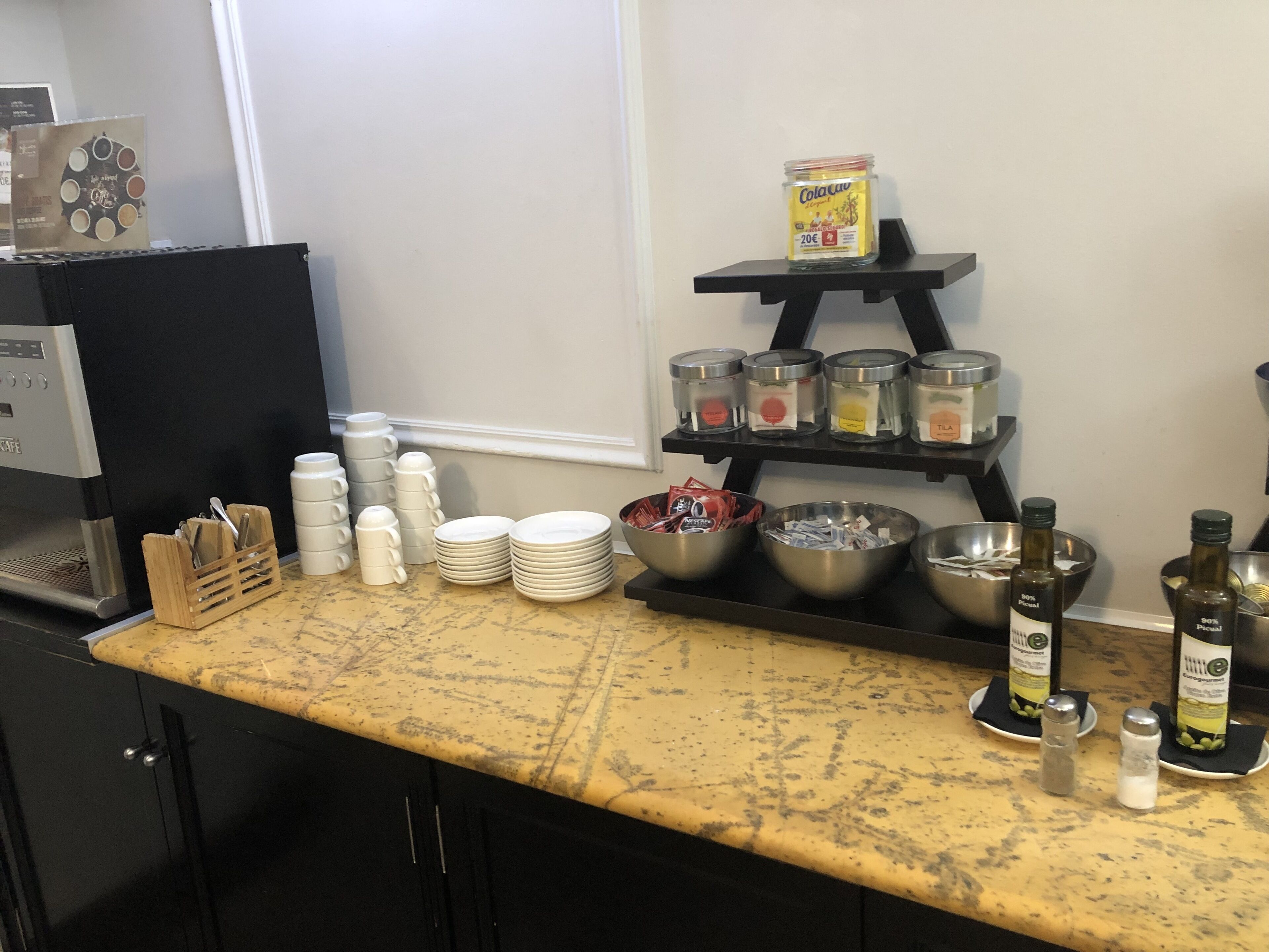 Un comptoir de cuisine avec une machine à café, une pile d’assiettes, des bols et des pots à condiments.