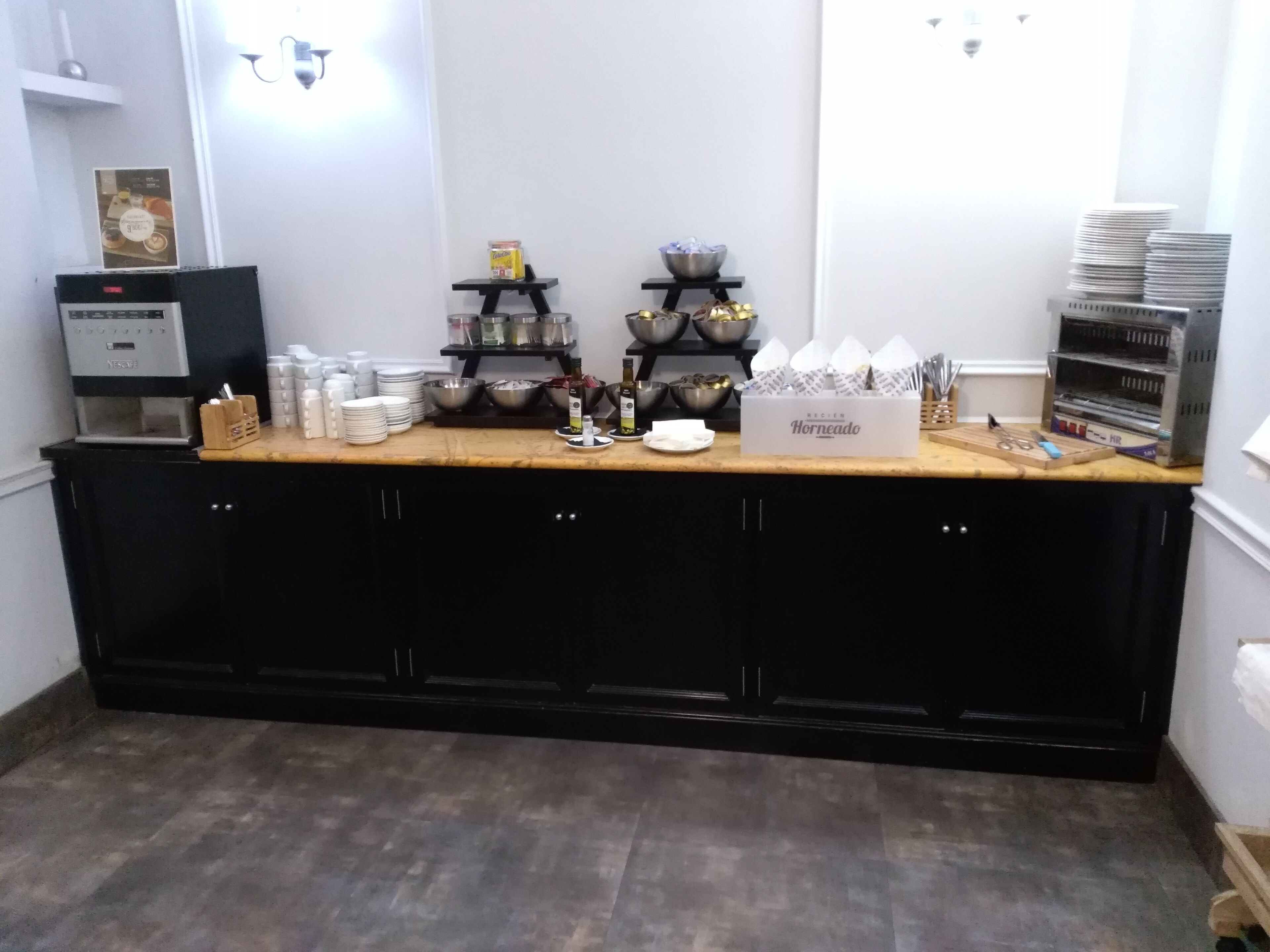 Et tekøkken med kaffemaskine, skåle, tallerkener og en kasse med teksten 'Horneado'.