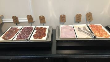 Mostrador de charcutería con diversos tipos de carnes y tomates etiquetados.