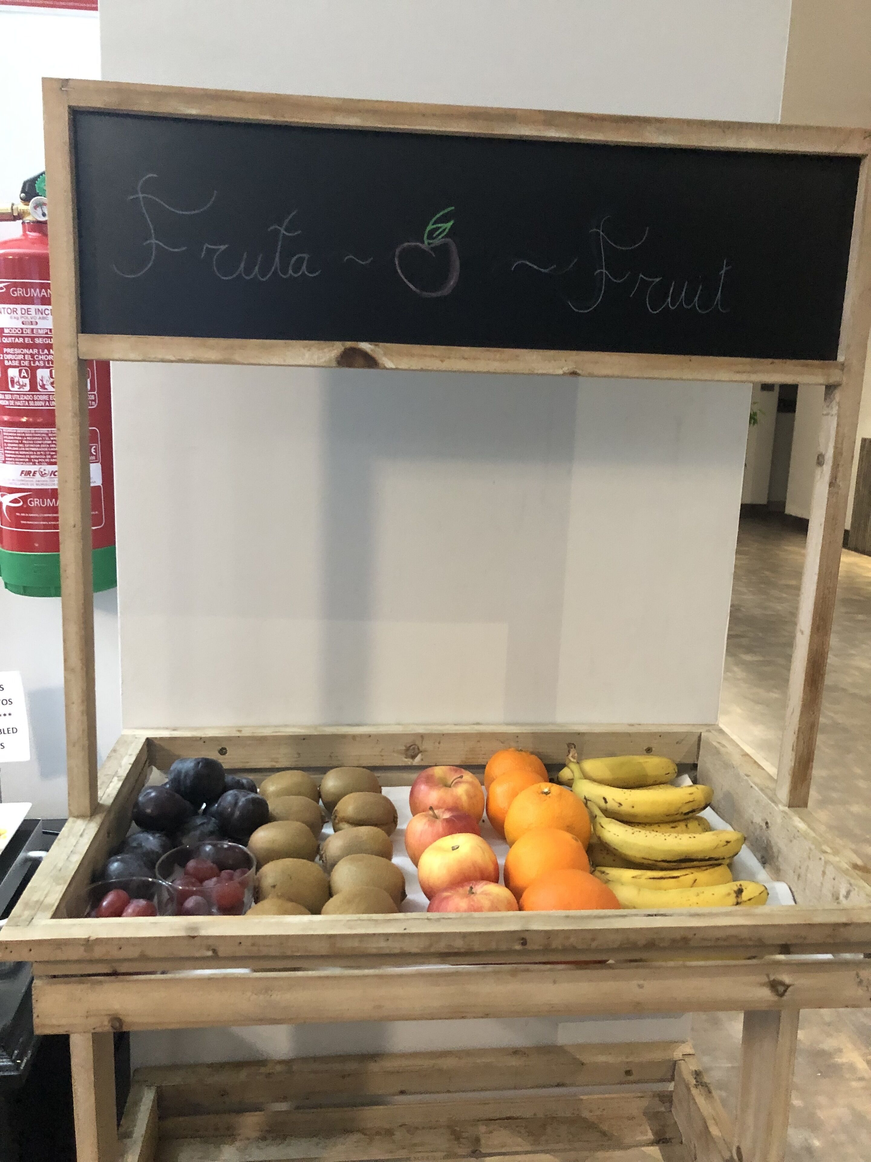 Un puesto de madera para frutas con un cartel de pizarra que dice 