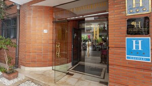 A hotel entrance with a glass door, a brick facade, and signage indicating it is part of the Hotel Accor Monteolivos chain. - Hotel AACR Monteolivos (Seville)