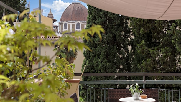 Ein Balkon mit Blick auf ein Gebäude mit einer Kuppel, umgeben von Grün.