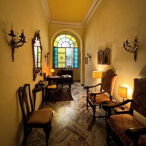 A warmly lit room with a dining table, chairs, and a large arched window. - Hotel Cestelli (Florence)