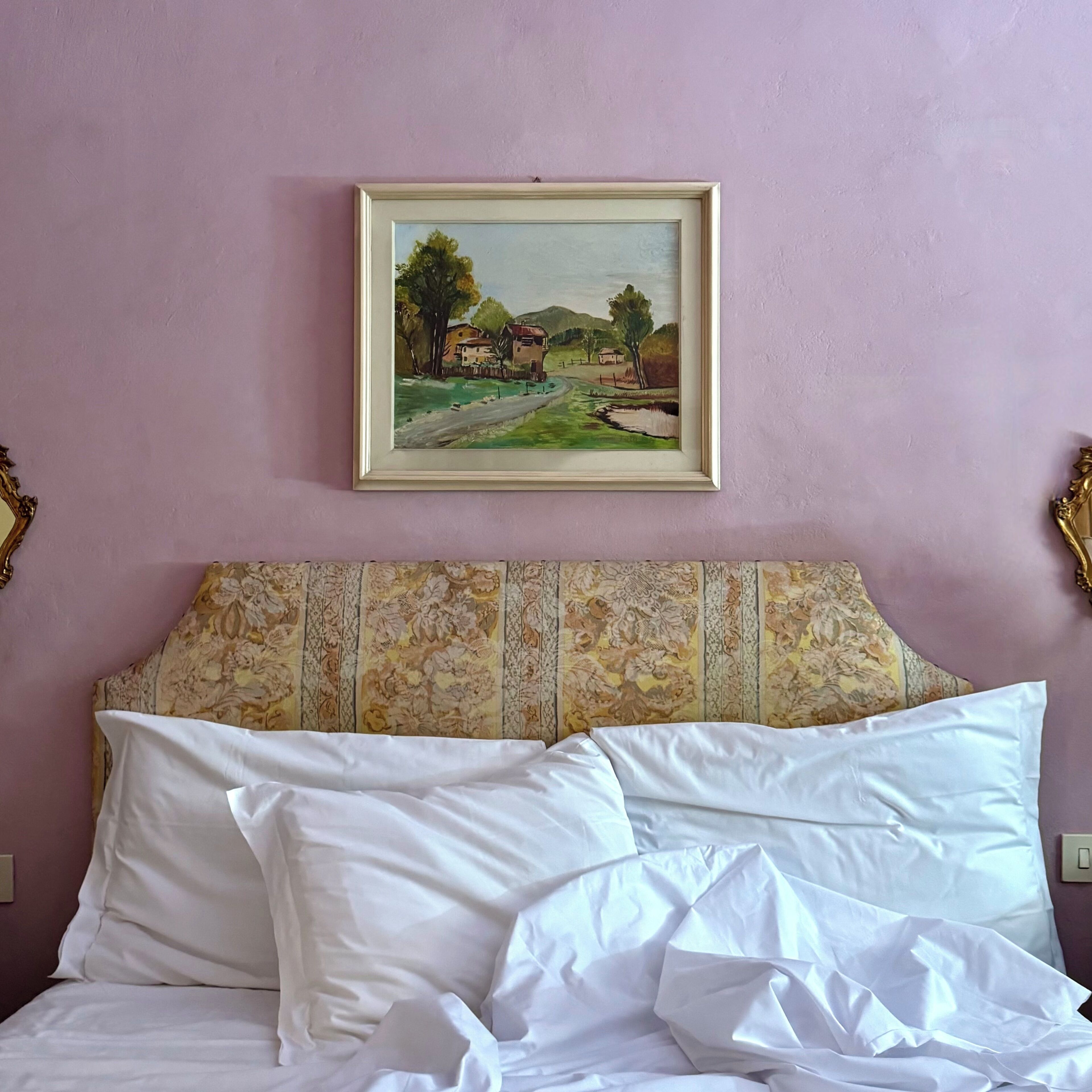 A bed with white linens and a floral-patterned headboard.