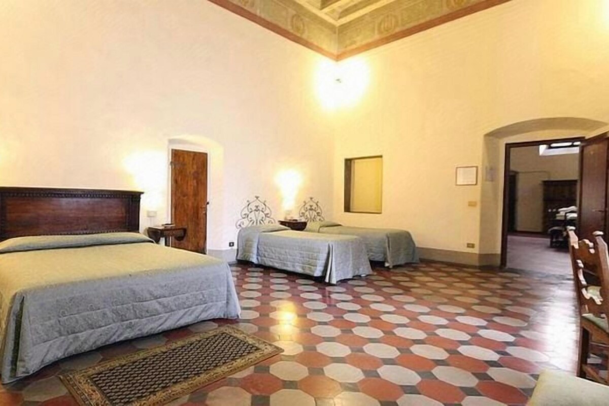 A hotel room with two beds, a patterned floor, and a wooden headboard.