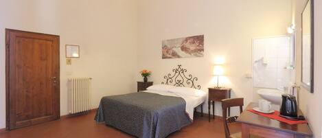 A bedroom with a bed, a desk with a chair, a radiator, a wooden door, and a painting on the wall.