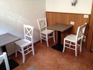 Una habitación pequeña con una mesa de madera y dos sillas blancas.