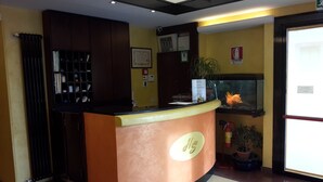 Un comptoir d’accueil avec une pancarte indiquant « Asg », une plante en pot, un extincteur et un certificat encadré accroché au mur.