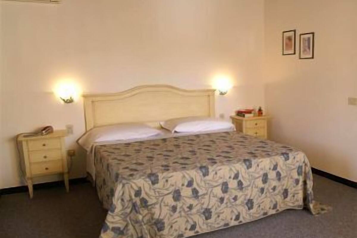A standard hotel room with a single bed, bedside tables, and wall-mounted lamps.