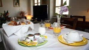 Una mesa de desayuno con cruasanes, jugo y tazas de café.