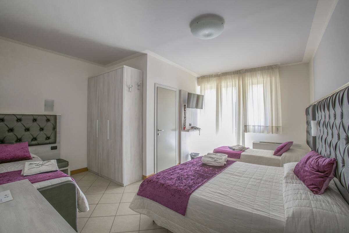 A hotel room with two beds, a wardrobe, a television, and a bathroom.