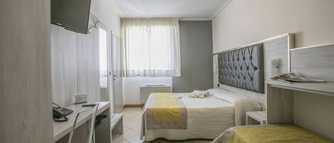 Une chambre d’hôtel avec deux lits, un bureau avec une chaise, une télévision et une fenêtre avec des rideaux.