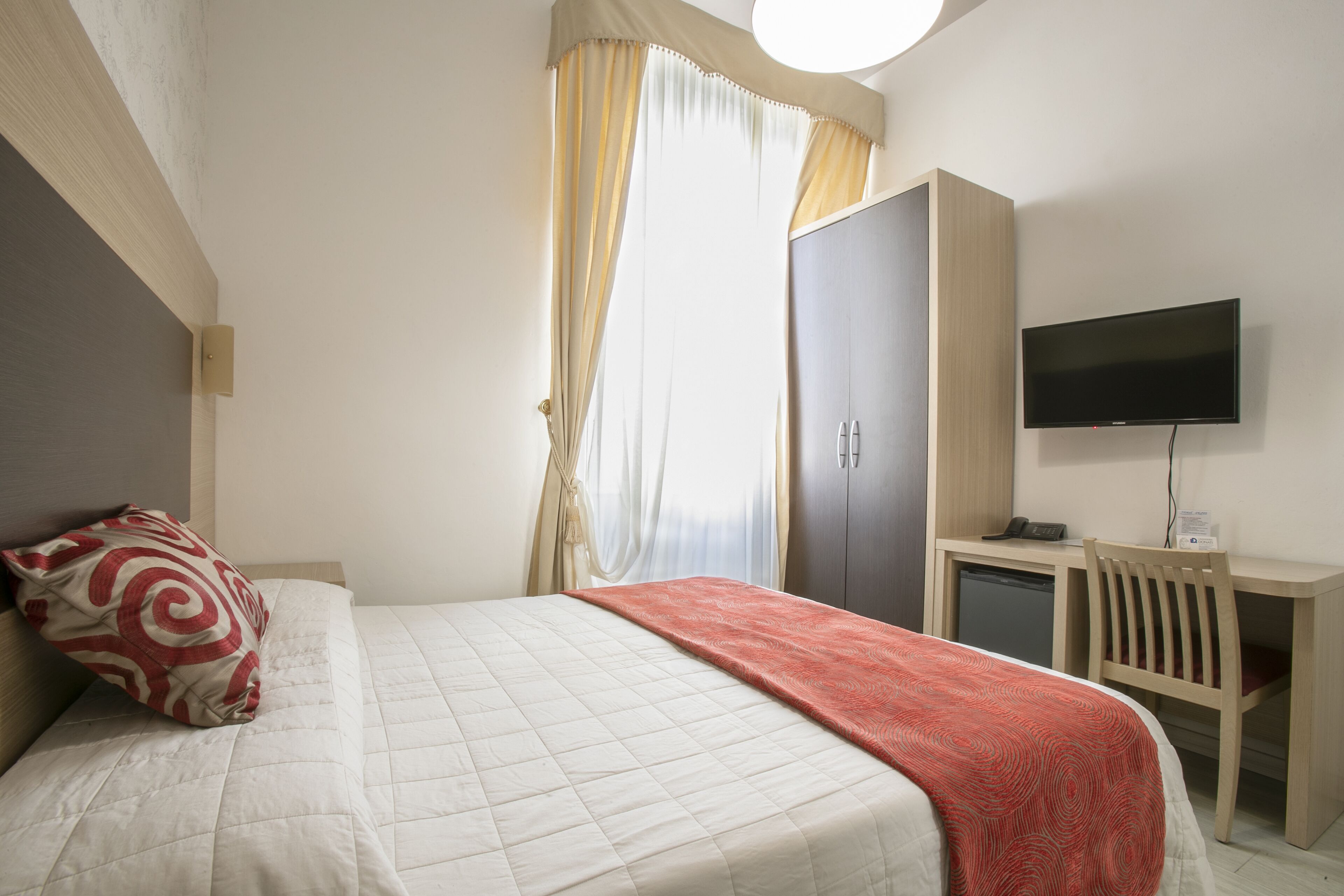 Un dormitorio con cama, televisor, escritorio y armario.