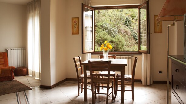 A dining area with a table and chairs, a window with curtains, and a lamp.