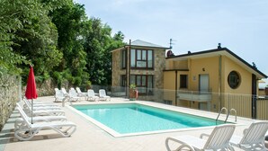 A swimming pool with lounge chairs and a red umbrella.