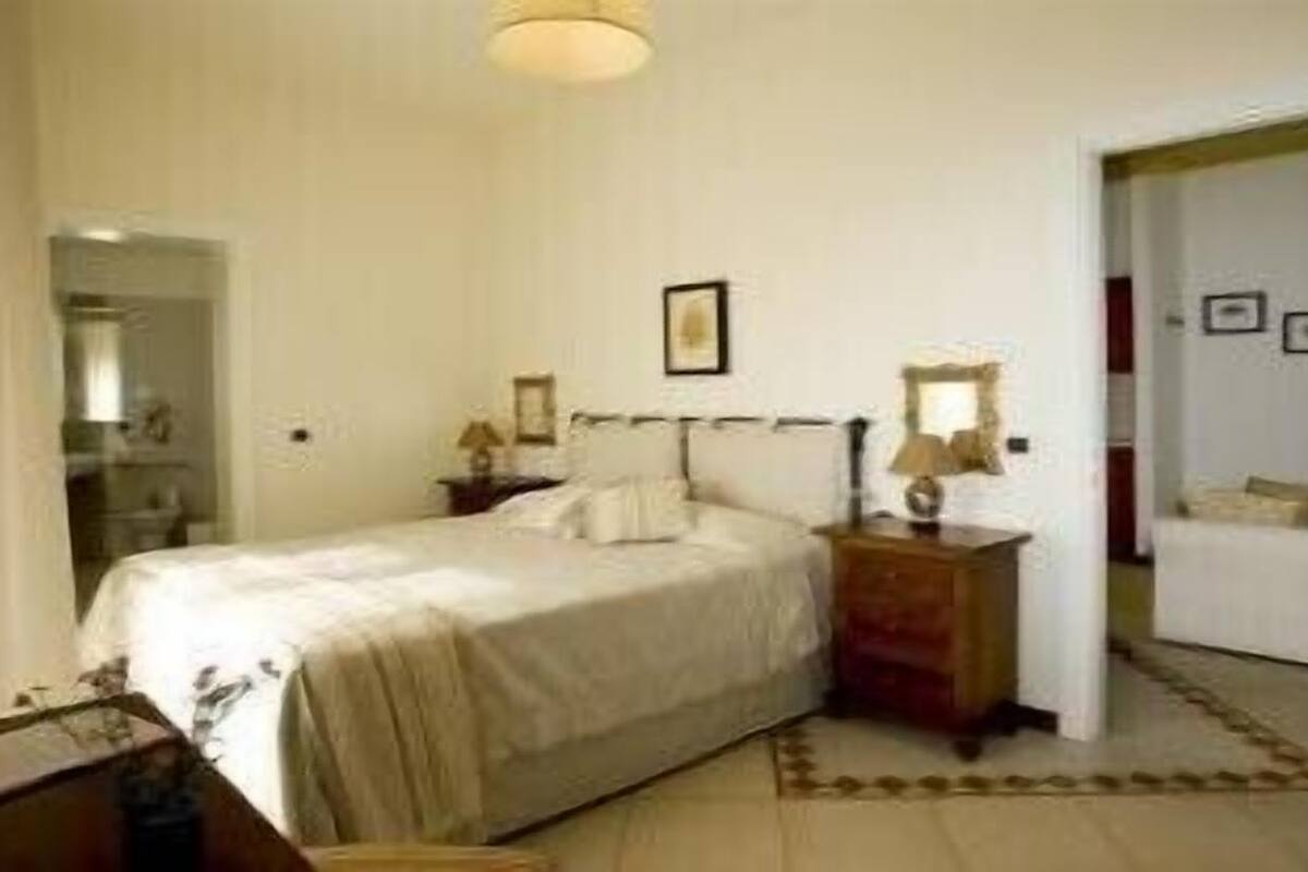 A bedroom with a bed, bedside tables, a lamp, and a mirror.
