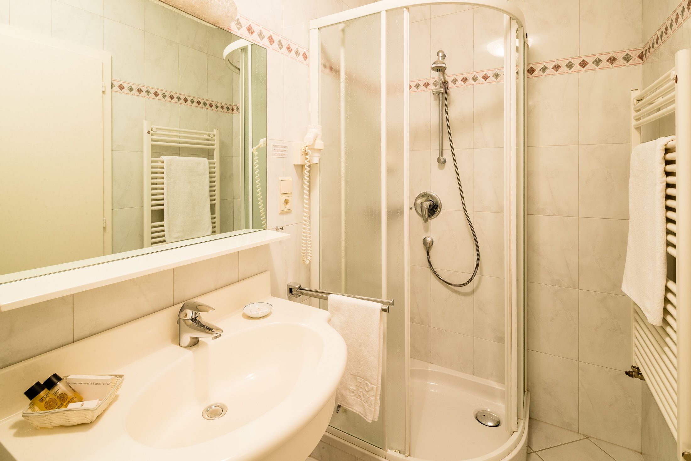Baño con lavamanos, espejo y ducha.