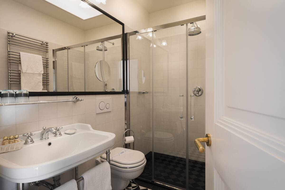 A modern bathroom with a glass-enclosed shower, a white sink, and a toilet.