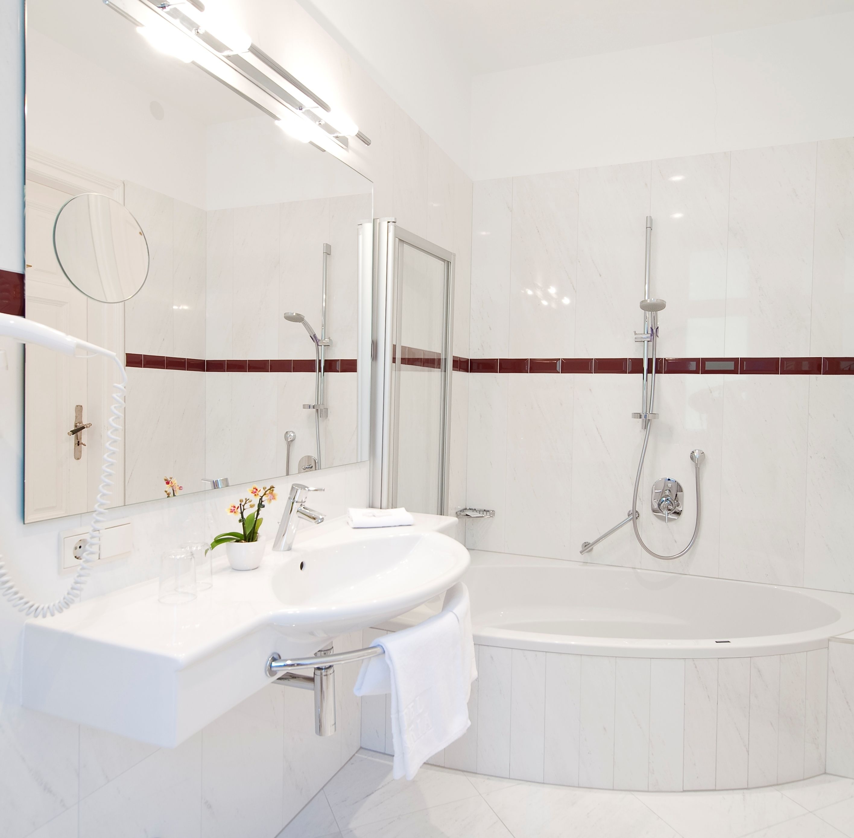 A modern bathroom with a large bathtub, a separate shower area, a vanity with a mirror, and a telephone.