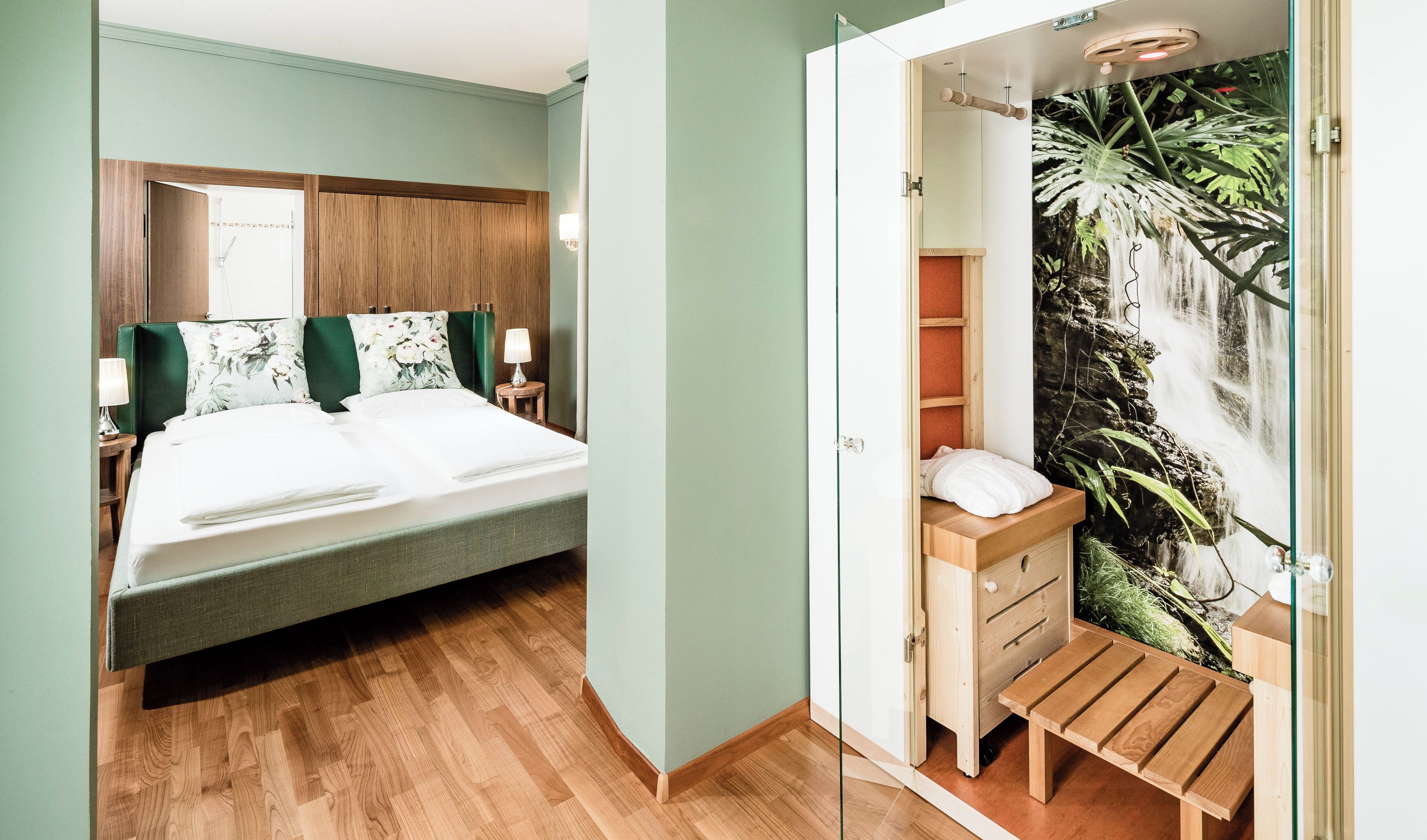 A bedroom with a bed, nightstands, a wooden bench, and a wall with a waterfall mural.