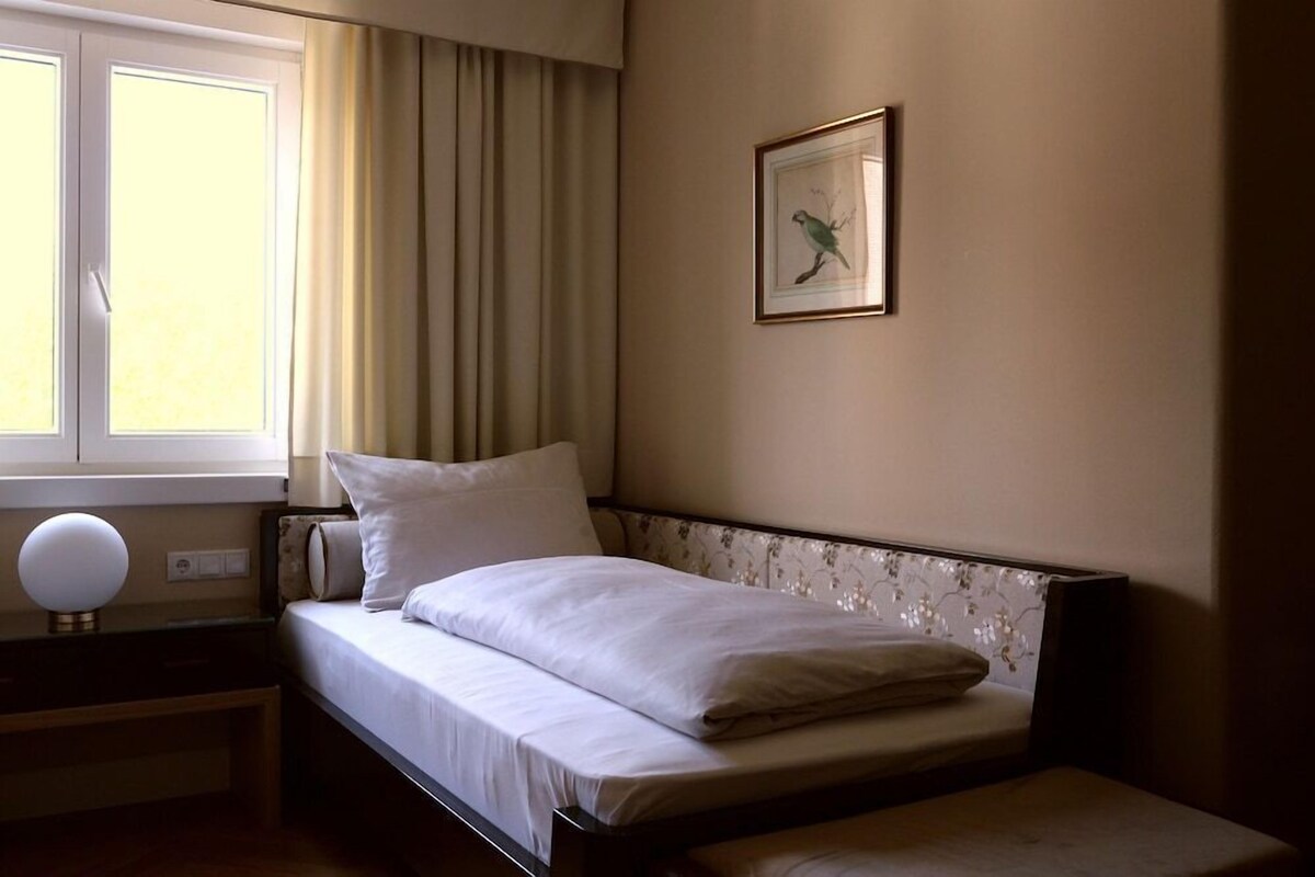 A neatly made bed with a pillow, a bedside lamp, and a framed picture on the wall.