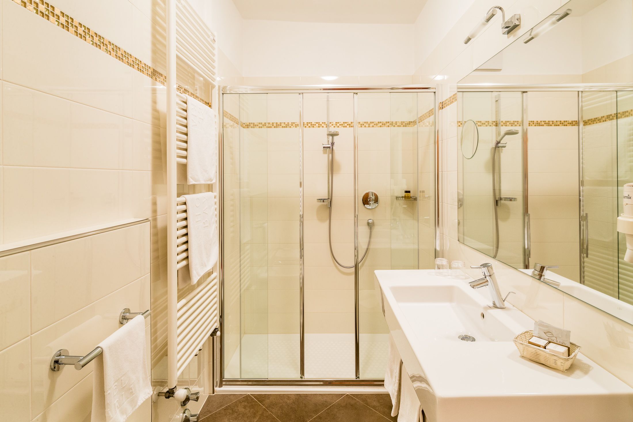 Een moderne badkamer met een douchecabine van glas, een witte wastafel en een grote spiegel.