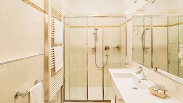 Een moderne badkamer met een douchecabine van glas, een witte wastafel en een grote spiegel.